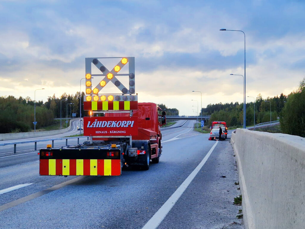 Hinausauto varoitusvalotaululla moottoritiellä